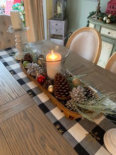 a dining room table with a candle and pine cones on it