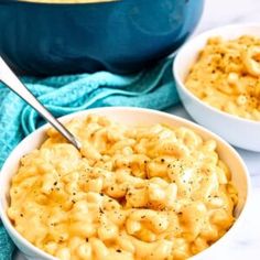 two bowls filled with macaroni and cheese on top of a white countertop