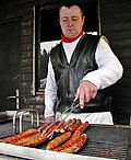 a man is grilling hot dogs on the grill with a knife and tongs