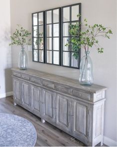 two vases with green plants are sitting on a dresser in front of a mirror