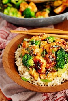 a bowl filled with chicken and broccoli on top of rice next to chopsticks