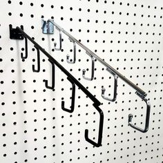 there is a metal rack with hooks on the wall next to polka dot pegboards