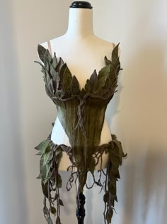 a mannequin is adorned with green leaves