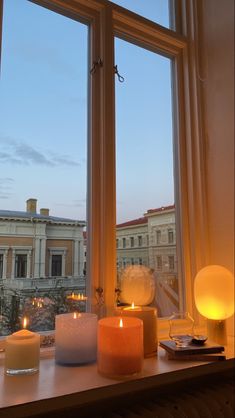 candles sit on a window sill in front of a large window