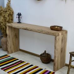 a wooden bench sitting on top of a white floor next to a rug and table