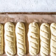 four loaves of bread lined up on a baking sheet in the process of being baked