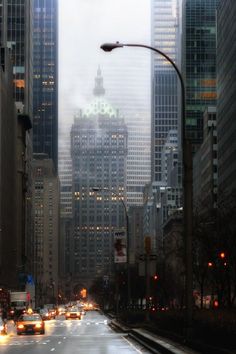 a city street filled with lots of traffic and tall buildings in the foggy night