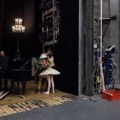 a woman in a white tutu holding a bouquet of flowers standing next to a piano