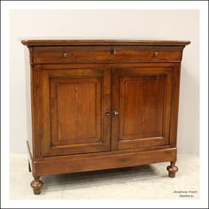 an old wooden cabinet with two doors and one drawer on the bottom, against a white wall