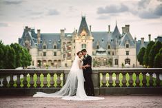 a bride and groom standing in front of a castle