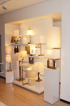 a room filled with lots of lamps on top of wooden floor next to white walls