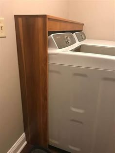 a washer and dryer in a small room with wood paneling on the floor