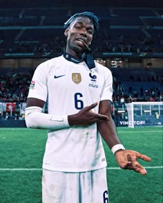 a man standing on top of a soccer field holding his hands out in front of him