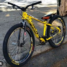 a yellow and black bike parked on the side of a road next to a tree