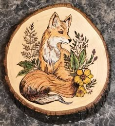 a wooden plate with an image of a fox and flowers painted on the front side