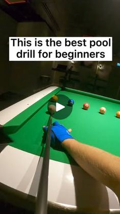 a pool table with balls and cues being held by a person's hand