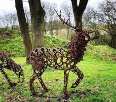 two metal deer sculptures sitting on top of a lush green field