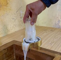 a person is pouring something into a blender on a wooden table with gold trim