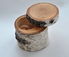 two wooden rings sitting inside of a tree stump container on a white surface with one ring in it's center