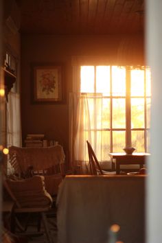 the sun shines through two windows in a living room with chairs and a table