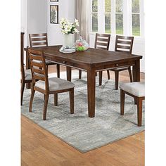 a dining room table with six chairs and a rug in front of the window,