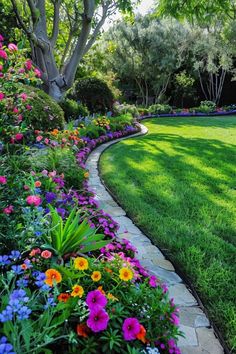 a garden with lots of flowers and trees in the background, along side a stone path