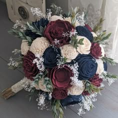 a bridal bouquet with red, white and blue flowers on the floor in front of a door