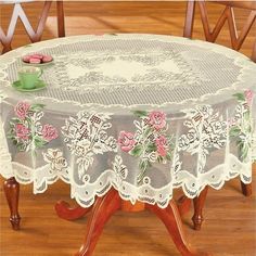 a table with a lace doily on top of it and pink flowers in the center