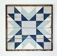 a wooden wall hanging with a blue and white patchwork star design on it's side