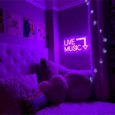 a bed in a room with purple lighting and pillows on the bed, next to a neon sign that reads live music