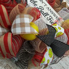 a close up of a wreath made out of burlocks and ribbons on a wooden surface