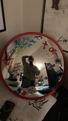 a man taking a selfie in a mirror with stickers all over the frame