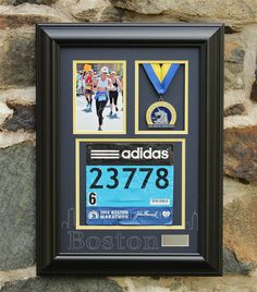 a framed marathon medal display on a stone wall next to a brick wall with photos and medals