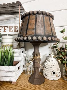 a lamp sitting on top of a wooden table next to potted plants and boxes