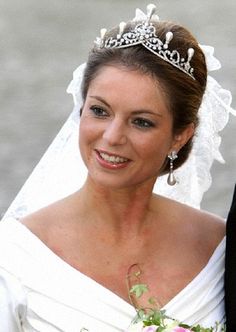 the bride is wearing a tiara and holding her bouquet