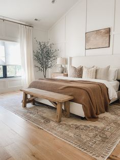 a bedroom with a bed, bench and window in the corner that overlooks an outdoor deck