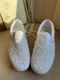 a pair of white shoes with pearls on them