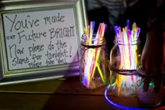 two mason jars filled with neon colored straws next to a framed sign that says we made future bright