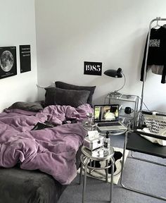 a bed sitting in a bedroom next to a table with a laptop on top of it