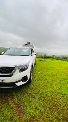 a white car parked on top of a lush green field