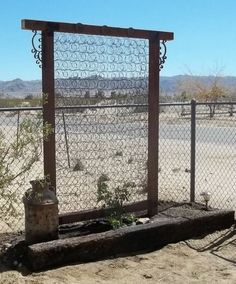 a fenced in area with a metal gate and planter on the other side