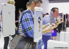 people standing around looking at cell phones in an apple store with their hands on the display