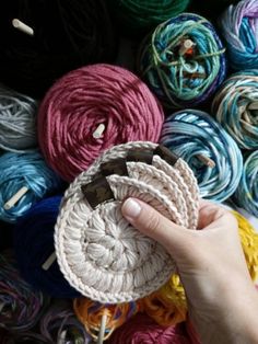 a person holding yarn in front of many skeins