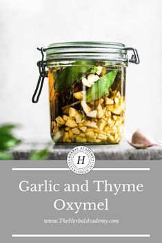 garlic and thyme oxyml in a glass jar with green leaves on the side