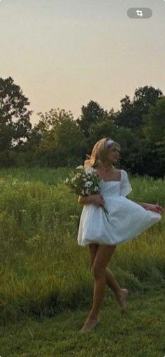 a woman in a white dress is walking through the grass