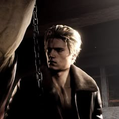 a young man with blonde hair wearing a black jacket and holding a chain in front of his face