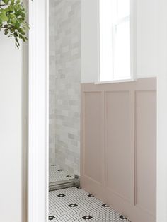 a bathroom with white walls and black and white floor tiles on the floor, next to a window