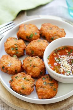 a white plate topped with tater tots next to a bowl of dipping sauce