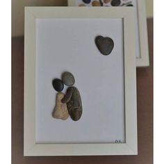 two rocks in a white frame on a table with some pictures and a heart shaped rock