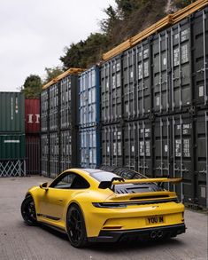 the yellow sports car is parked in front of some shipping containers and cargo bins